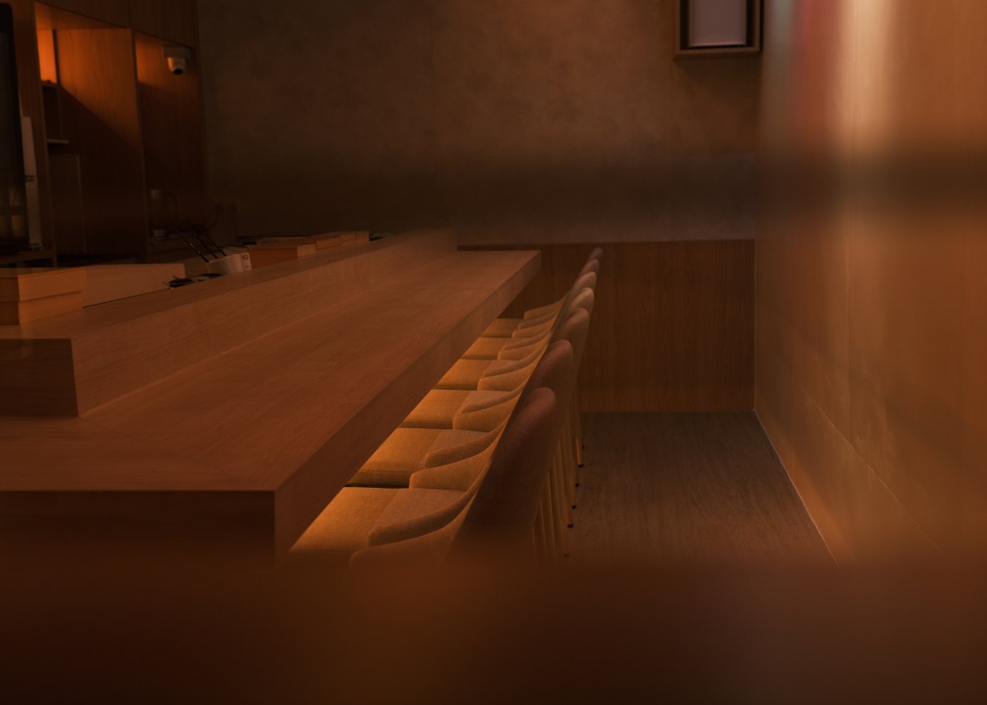 An omakase sushi counter with seats set along a wooden bar
